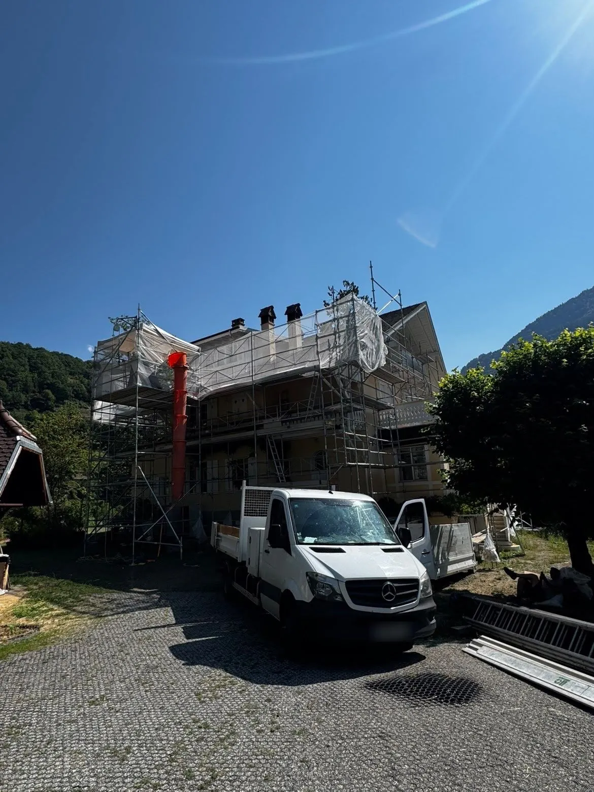 Échafaudage, goulotte à gravats et camion benne sur un chantier de toiture