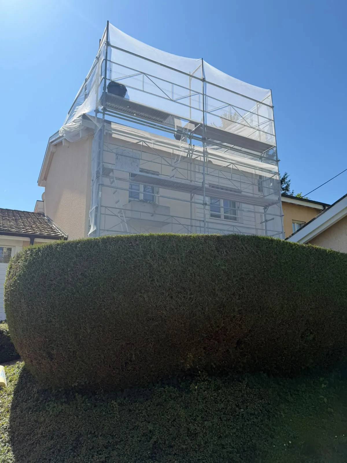 Échafaudage de façade sur pied sous filet de protection monté contre une maison