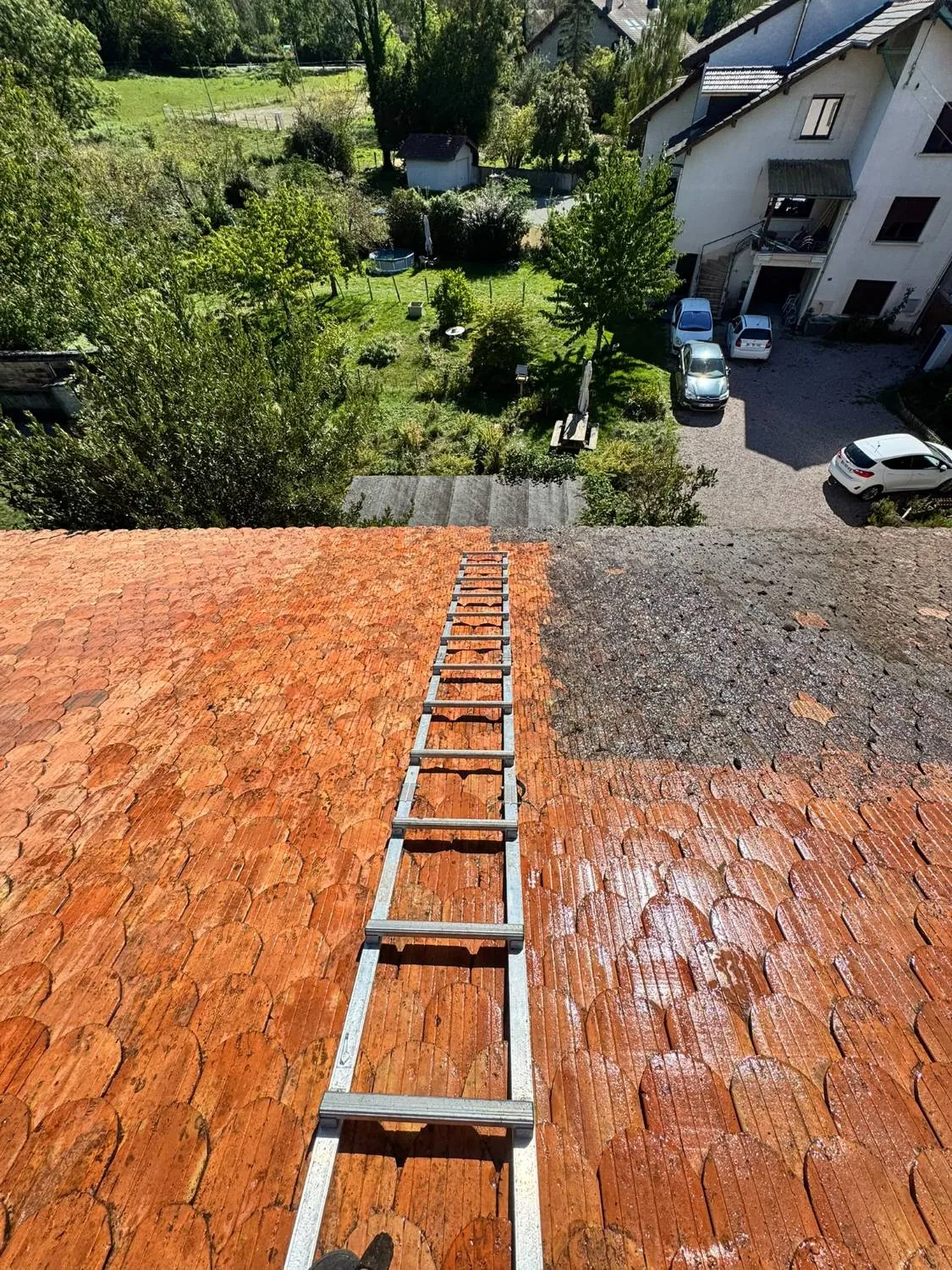 Nettoyage de toiture en cours : tuiles nettoyées, zone encore encrassée en haut à droite