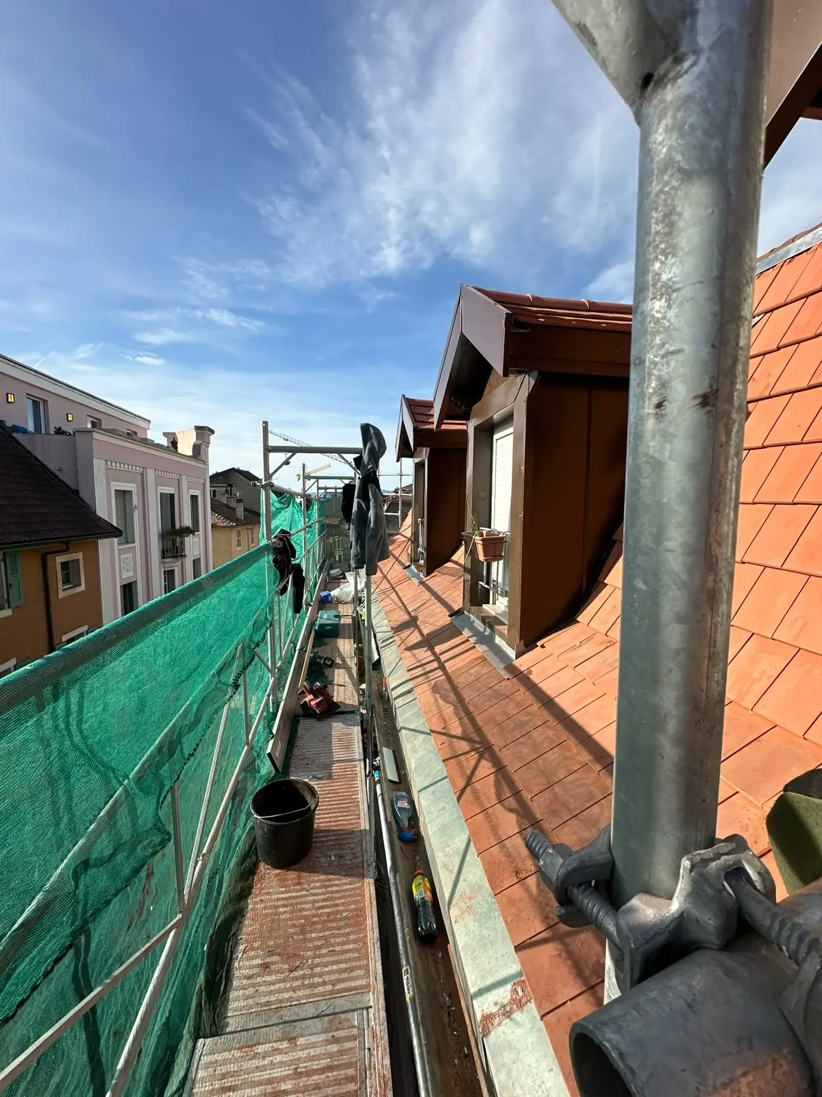 Toiture en tuiles plates et ses lucarnes, vue depuis la passerelle d'échafaudage d'un chantier DCK BATIPRO à Thonon-les-Bains